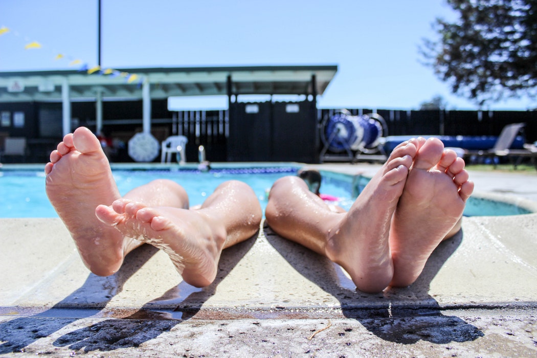 Two people with their feet sticking out of a pool.