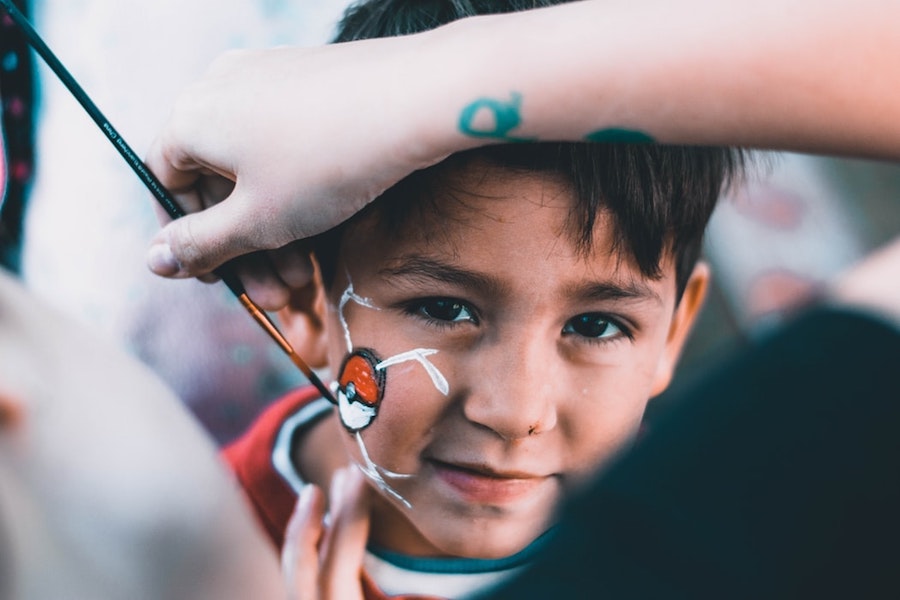 A young kid getting his face painted. 