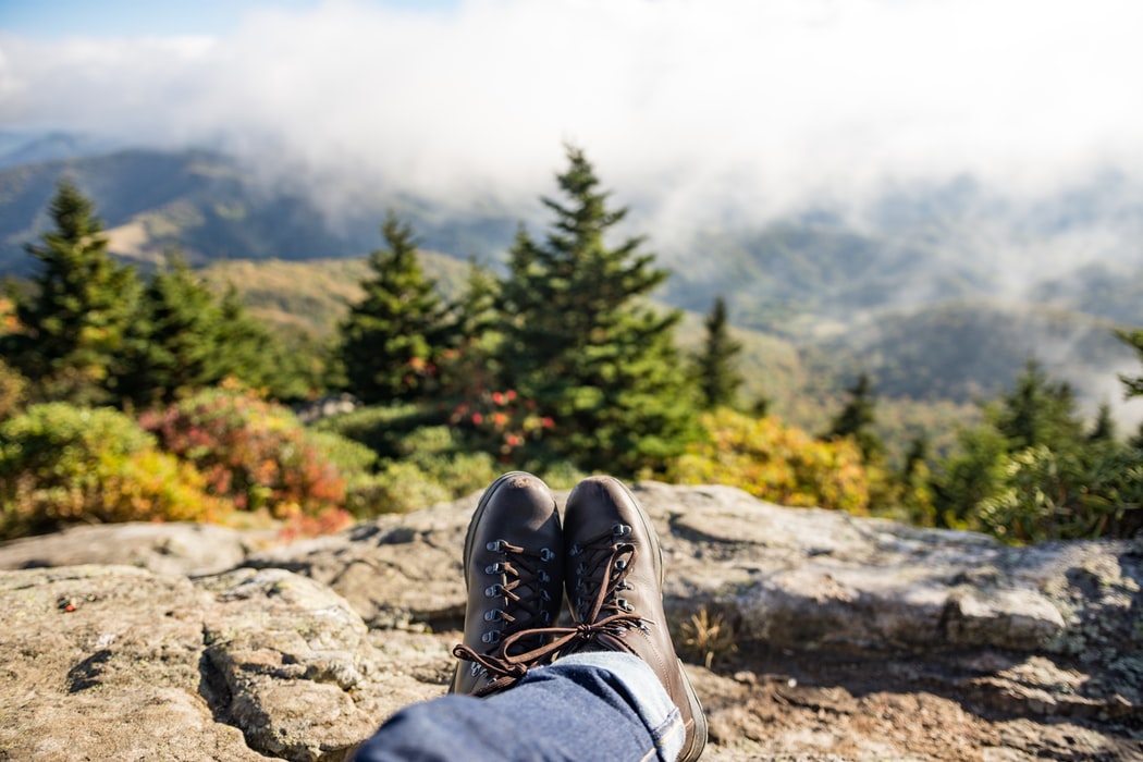 A person lounging on a rock above hills and mountains during the fall.