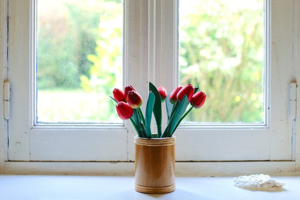 A flower vase sitting on a window sill.