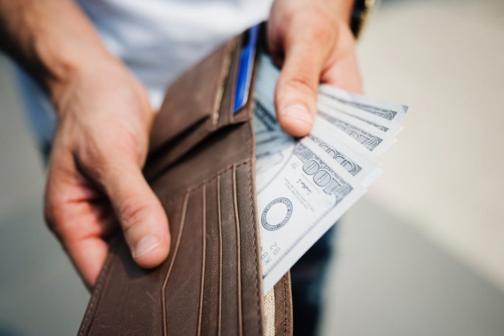 A man pulling money out of a wallet in order to complete his real estate resolutions.