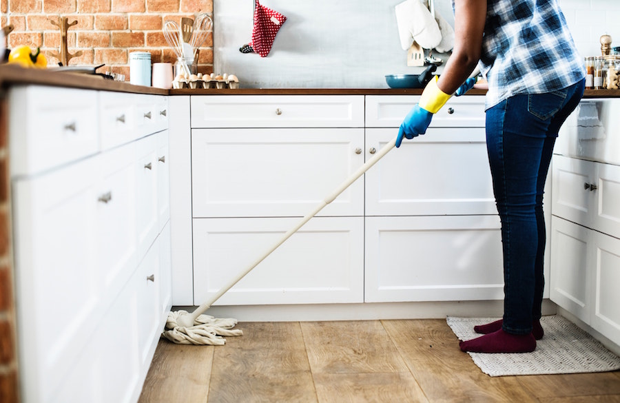 Person mopping the floor, and other things on a spring cleaning checklist for sellers.